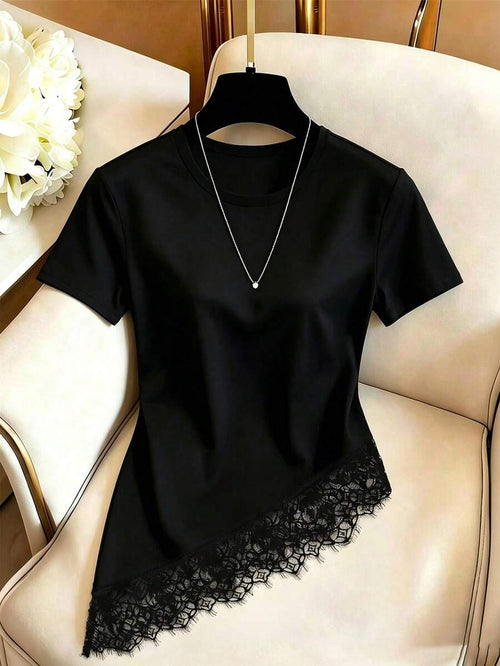 Blusa negra de manga corta con encaje asimétrico colgada en una percha sobre una silla.