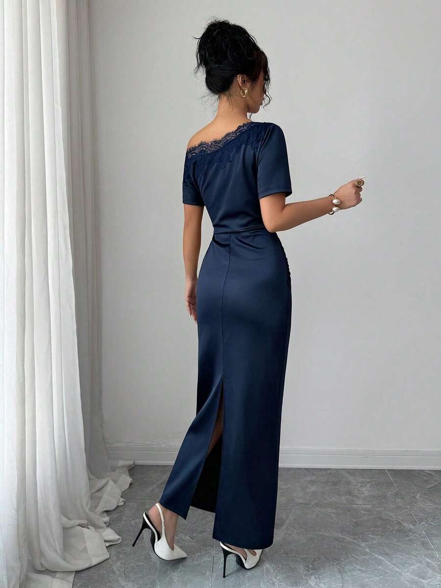 Mujer elegante vistiendo un vestido azul marino asimétrico con encaje en el hombro.