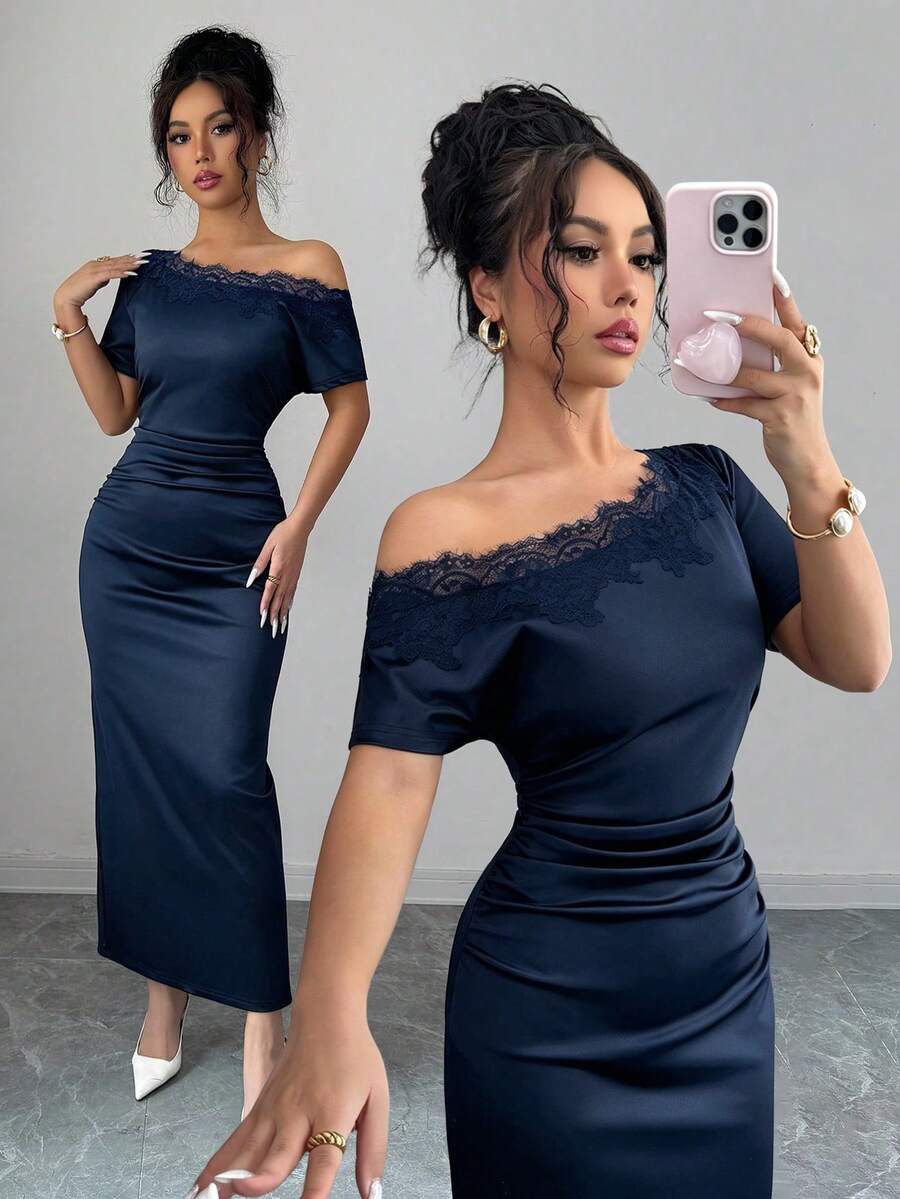 Mujer elegante vistiendo un vestido azul marino asimétrico con encaje en el hombro.