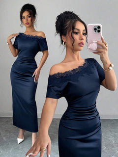 Mujer elegante vistiendo un vestido azul marino asimétrico con encaje en el hombro.