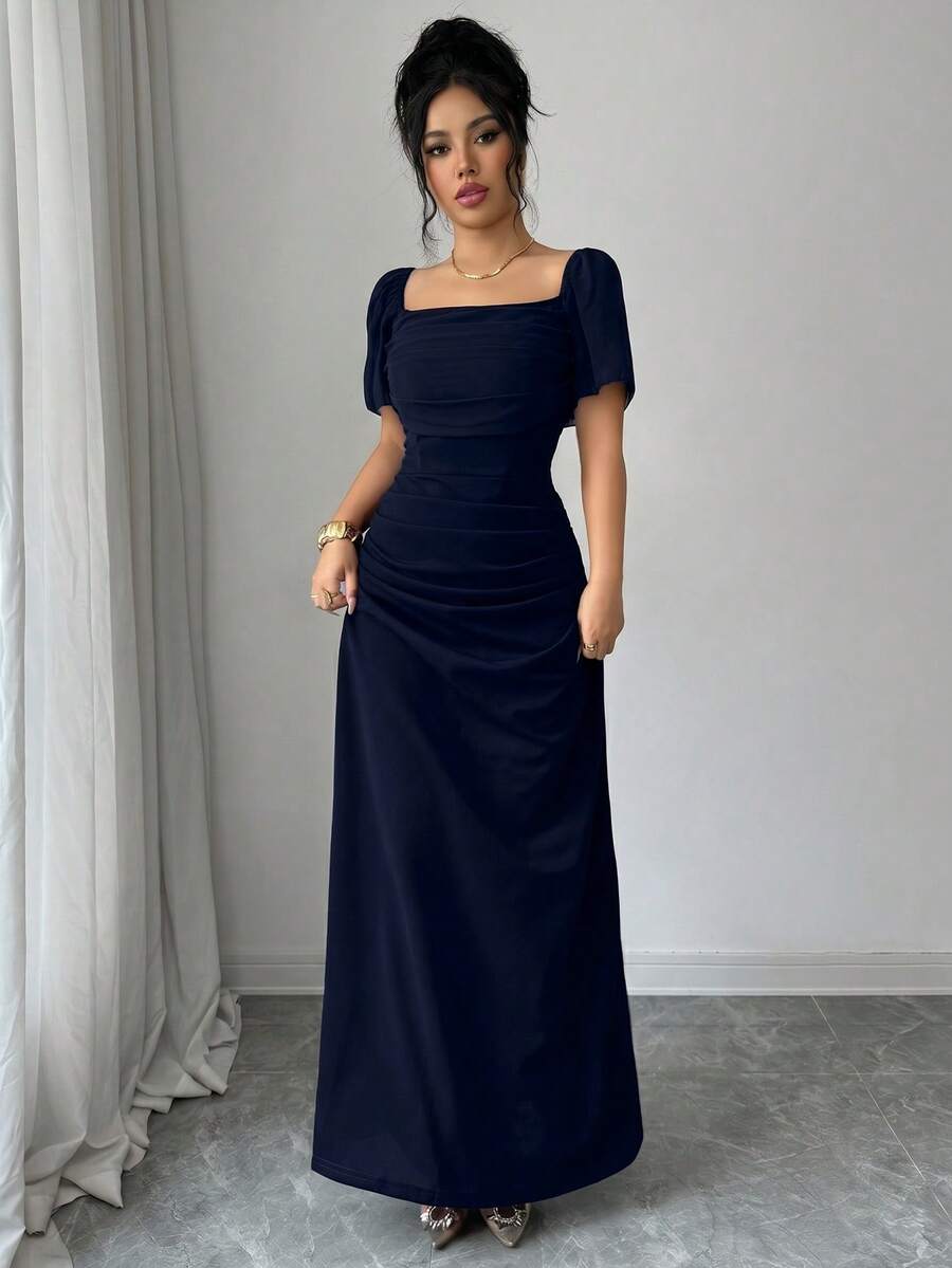 Vista frontal de una mujer luciendo un vestido largo elegante azul noche con escote cuadrado y mangas cortas abullonadas.