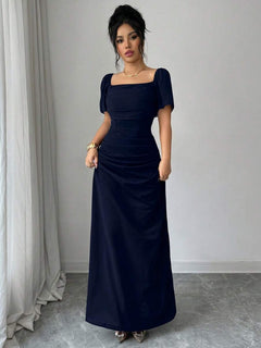 Vista frontal de una mujer luciendo un vestido largo elegante azul noche con escote cuadrado y mangas cortas abullonadas.