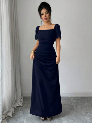 Vista frontal de una mujer luciendo un vestido largo elegante azul noche con escote cuadrado y mangas cortas abullonadas.