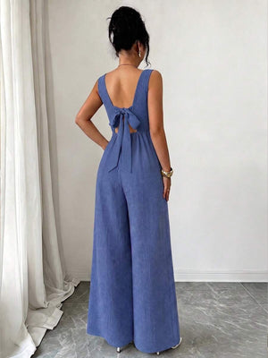 Primer plano del torso de un jumpsuit azul con cuello cuadrado y botones decorativos en la cadera.