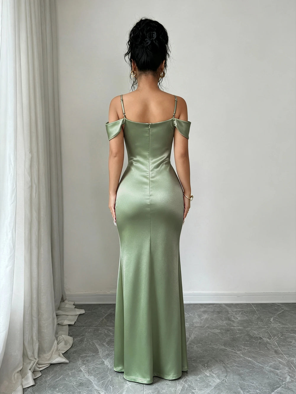 Mujer posando de frente con un vestido largo de fiesta satinado en color verde menta, con hombros descubiertos y abertura en la pierna.