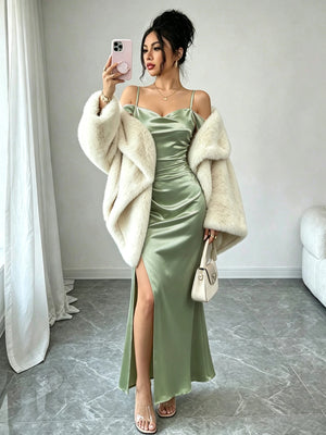 Mujer tomándose una selfie en un espejo luciendo un vestido largo satinado verde con escote drapeado y hombros descubiertos.