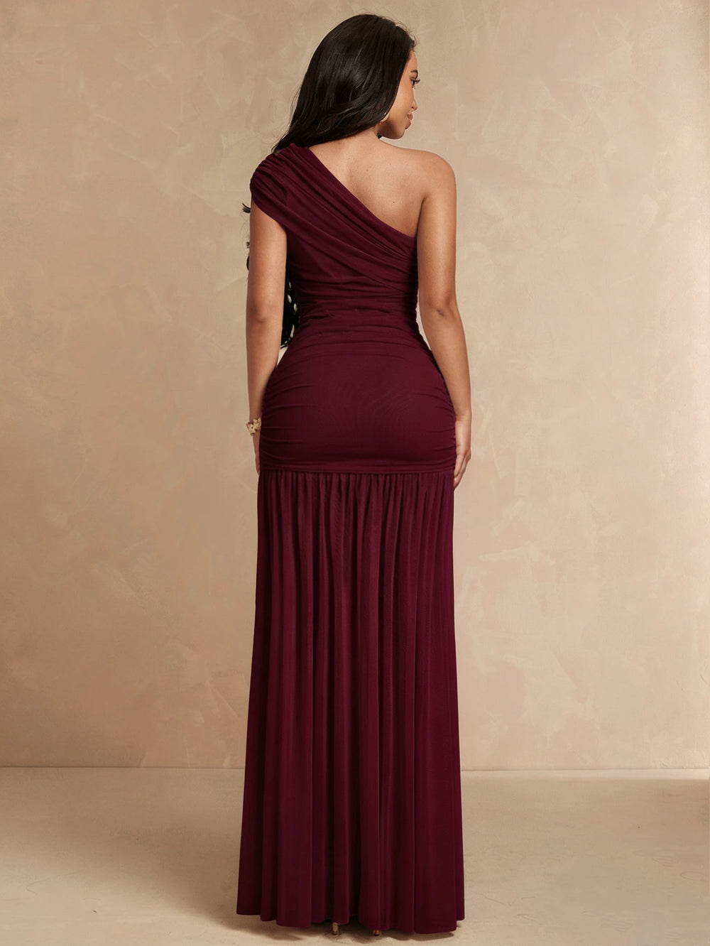 Mujer modelando un vestido largo de fiesta color vino con escote asimétrico de un solo hombro.