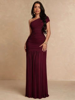 Mujer modelando un vestido largo de fiesta color vino con escote asimétrico de un solo hombro.