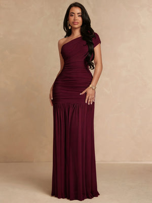 Mujer modelando un vestido largo de fiesta color vino con escote asimétrico de un solo hombro.
