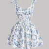 Vestido corto blanco con estampado floral azul y tirantes de lazo, ideal para ocasiones veraniegas.