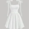 Vestido corto blanco con escote fruncido y tirantes de lazo, ideal para ocasiones veraniegas.