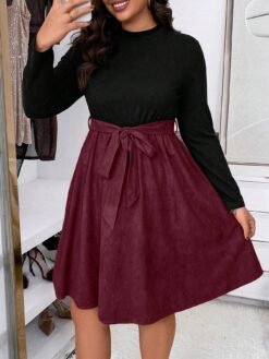 Mujer mostrando el cinturón ajustable en su vestido burdeos a línea.