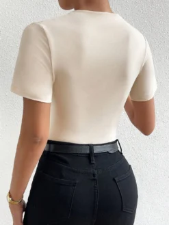 Vista trasera del body fruncido beige, combinado con pantalones negros ajustados.