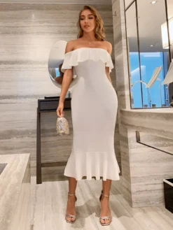 Modelo de pie luciendo vestido blanco con volante, mostrando el corte midi y elegante diseño.
