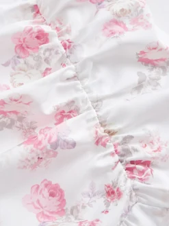 Primer plano del fruncido y los volantes del vestido floral blanco.