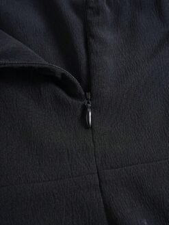 Detalle de la cremallera del mono largo negro.