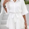 Mujer usando conjunto corto blanco con cinturón y cuello de camisa, estilo relajado.