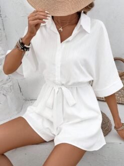 Mujer con sombrero y conjunto corto blanco con cinturón y cuello de camisa.