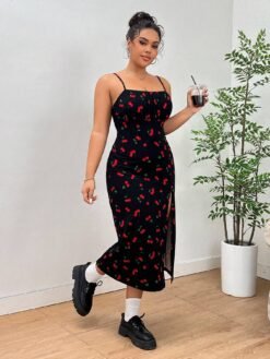 Modelo con el vestido midi de tirantes finos y estampado de cerezas, sujetando una bebida.