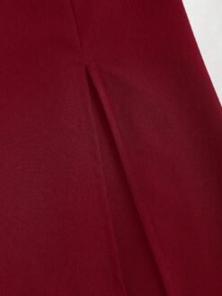 Detalle de la abertura del bajo del vestido burdeos.