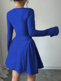 Mujer usando vestido corto azul elegante con escote corazón y mangas largas.