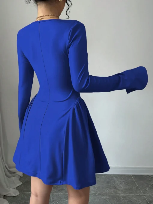 Mujer usando vestido corto azul elegante con escote corazón y mangas largas.