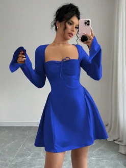 Mujer usando vestido corto azul elegante con escote corazón y mangas largas.