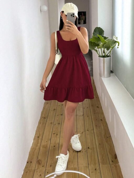 Mujer con vestido burdeos con escote scoop y bajo con volante, mostrando diseño completo.