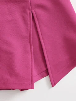 Detalle del diseño asimétrico y aberturas laterales de la falda.