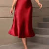 Falda midi roja satinada de talle alto con corte campana.