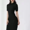 Mujer luciendo vestido negro ajustado con cuello alzado y corte lápiz.