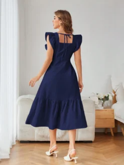 Vista trasera del vestido midi azul marino con diseño de volantes y detalle de nudo.