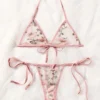 Set de lencería rosa romántico-floral bordado semitransparente sobre fondo blanco.