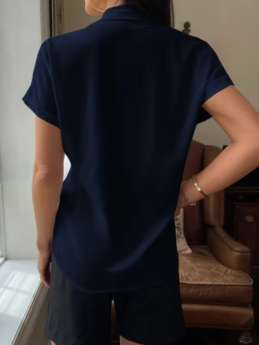 Vista trasera de la camisa azul marino, mostrando su corte redondeado.