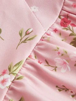 Primer plano del estampado floral en tonos rosa y verde, mostrando los detalles del tejido.