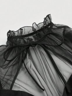 Primer plano del escote con corbata y transparencias del vestido negro elegante.