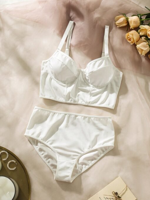 Set lencería blanca romántica colocado sobre fondo decorativo con rosas.