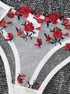 Primer plano de la tanga bordada del conjunto lencería blanco transparente.