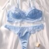 Set de lencería romántico floral azul con sujetador y tanga sobre fondo blanco.