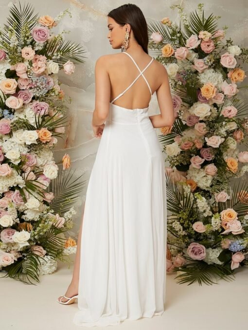 Espalda cruzada del vestido blanco largo con abertura alta en ambiente floral.