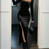 Modelo con vestido largo negro ajustado posando en interior moderno.