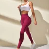 Modelo usando leggings deportivos burdeos con top blanco, caminando hacia adelante.