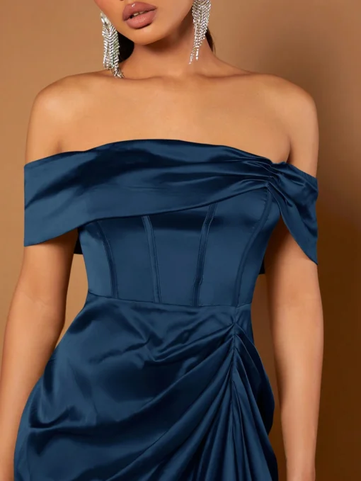 Modelo posando con el vestido azul marino ajustado y accesorios largos
