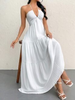 Mujer sentada luciendo vestido blanco halter fluido con corte a capas