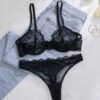 Set de lencería negro con encaje transparente sobre jeans claros.