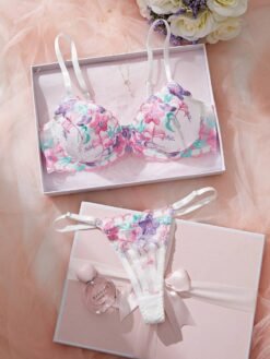 Set de lencería bordada multicolor con tanga y sujetador balconette sobre fondo rosa.
