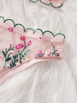 Detalle del bordado floral en el set de lencería rosa.