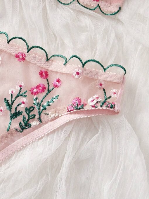 Detalle del bordado floral en el set de lencería rosa.