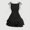 Vista frontal del vestido mini negro con tirantes y capas