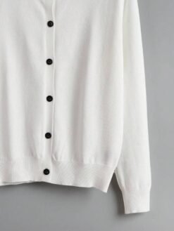 Detalle inferior del cardigan blanco básico con acabado acanalado.